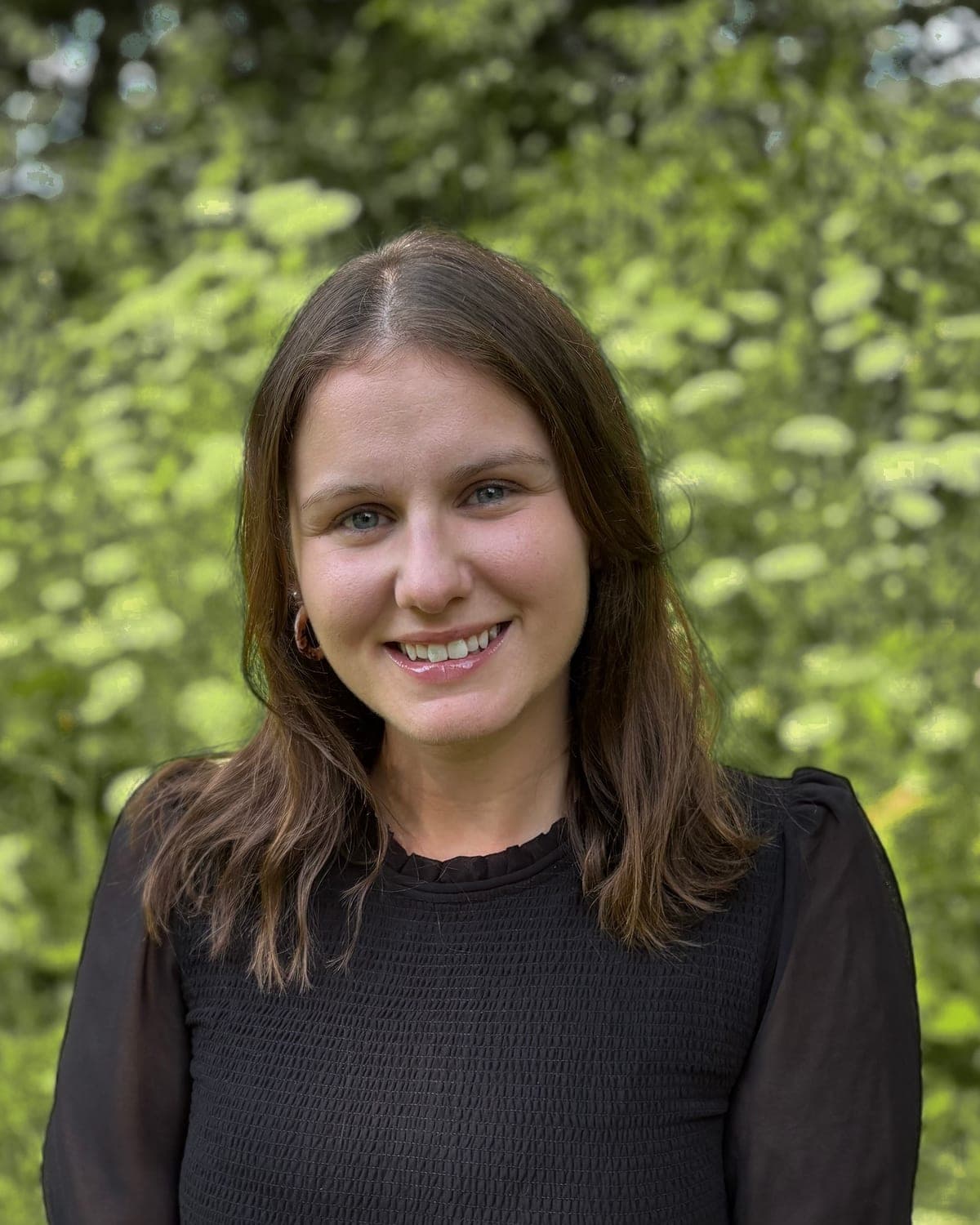 Jessica Ruppert, Registered Psychotherapist, outdoors in front of flowering shrubs